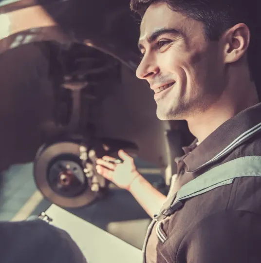 A man is smiling while holding a clipboard in front of a car