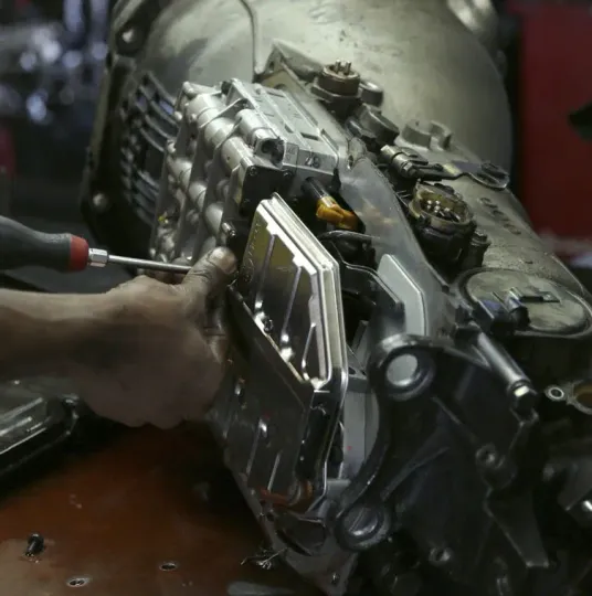 A man is working on a car engine with a screwdriver