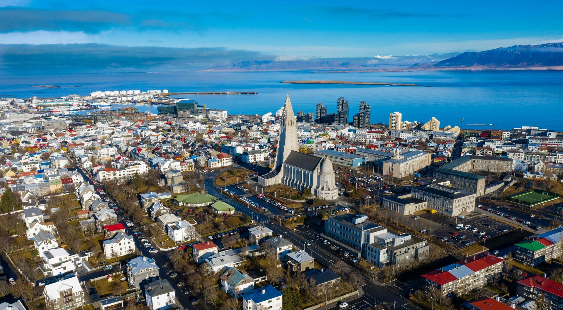 An aerial view of Reykjavik, Iceland, with the iconic Hallgrímskirkja church tower standing tall above the city buildings.
