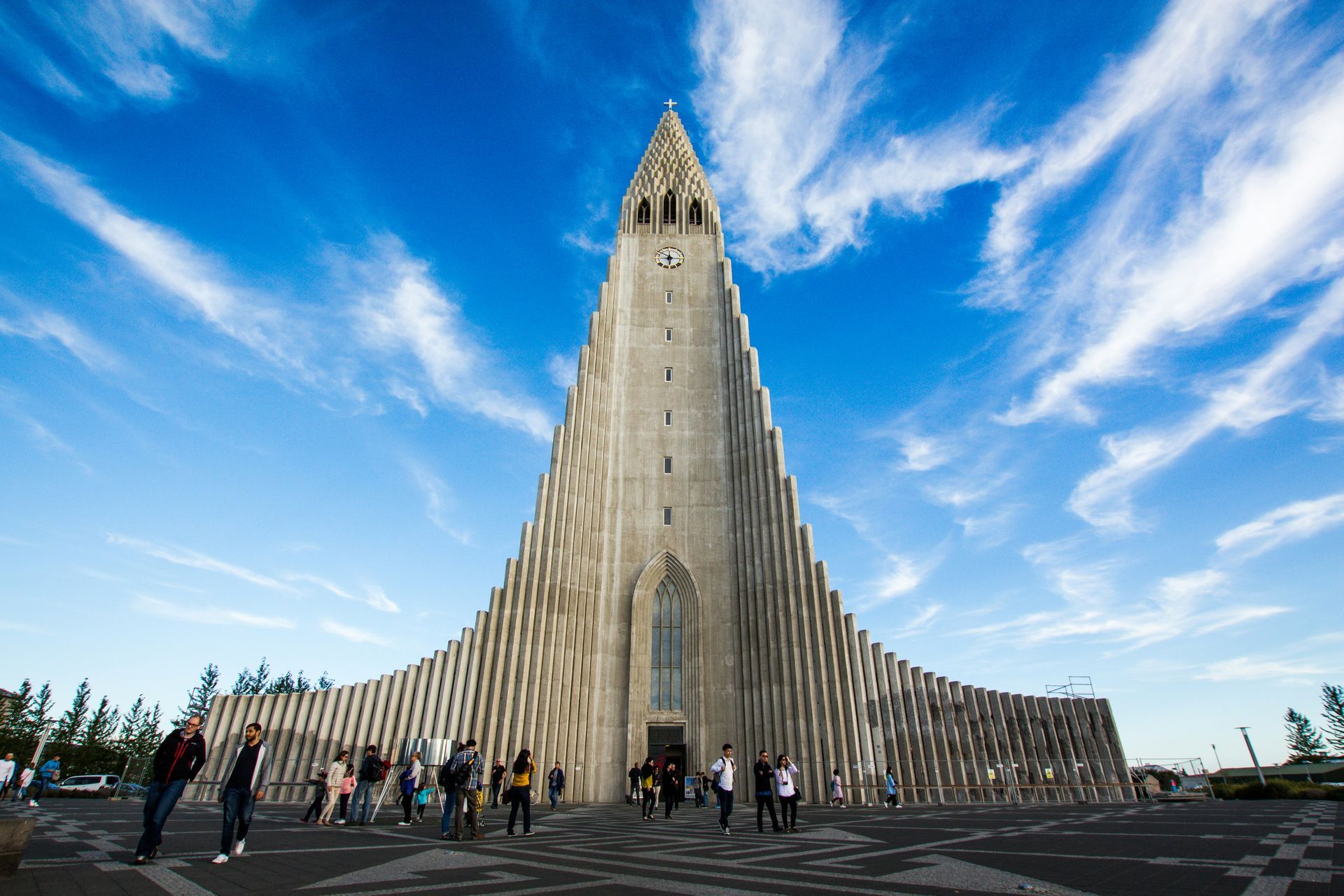 The Hallgrímskirkja church in Reykjavík, Iceland, with its distinctive concrete tiered tower under a blue, cloudy sky.