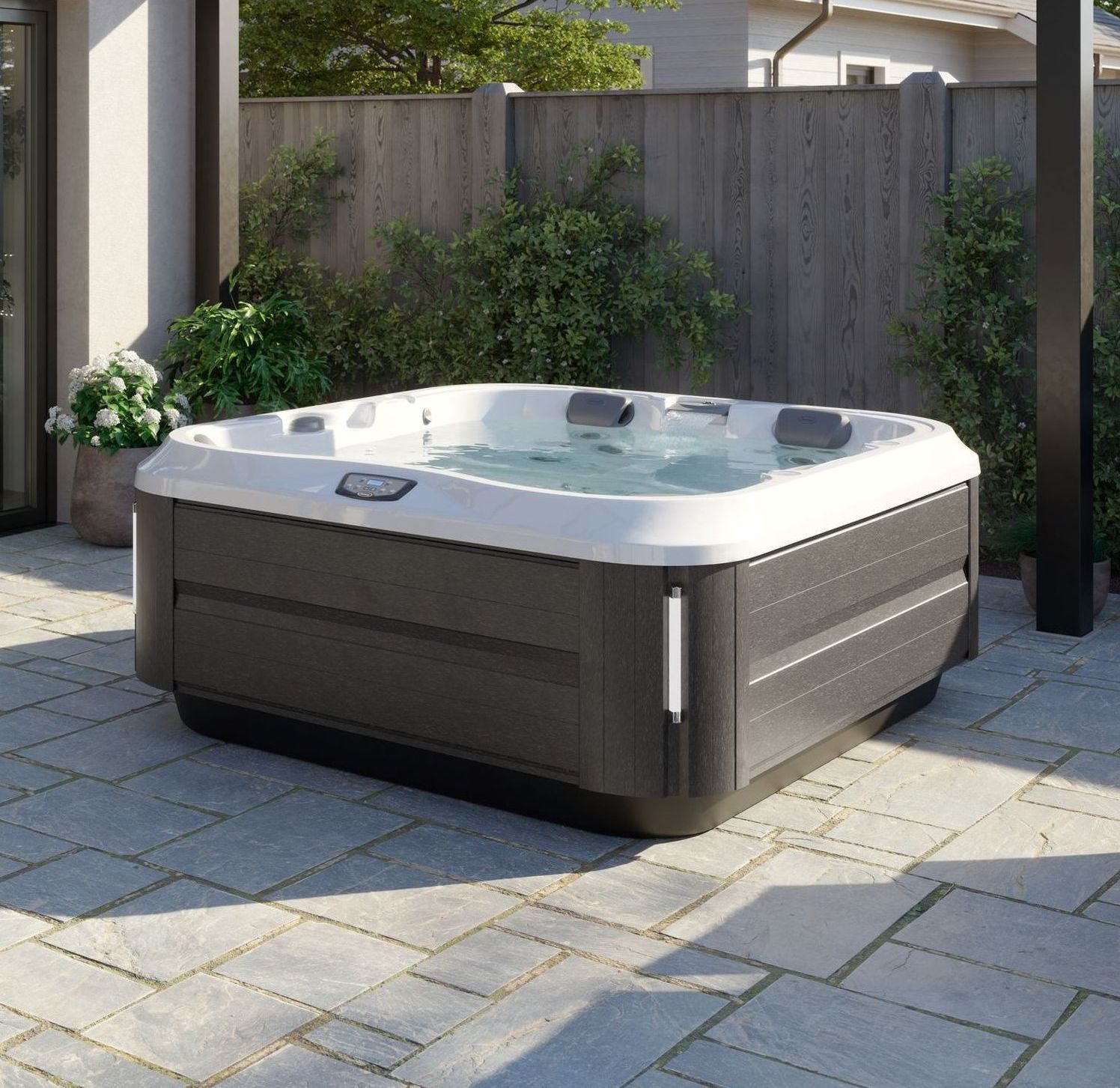 Hot tub on a stone patio with a dark gray exterior and white trim; set in a backyard.