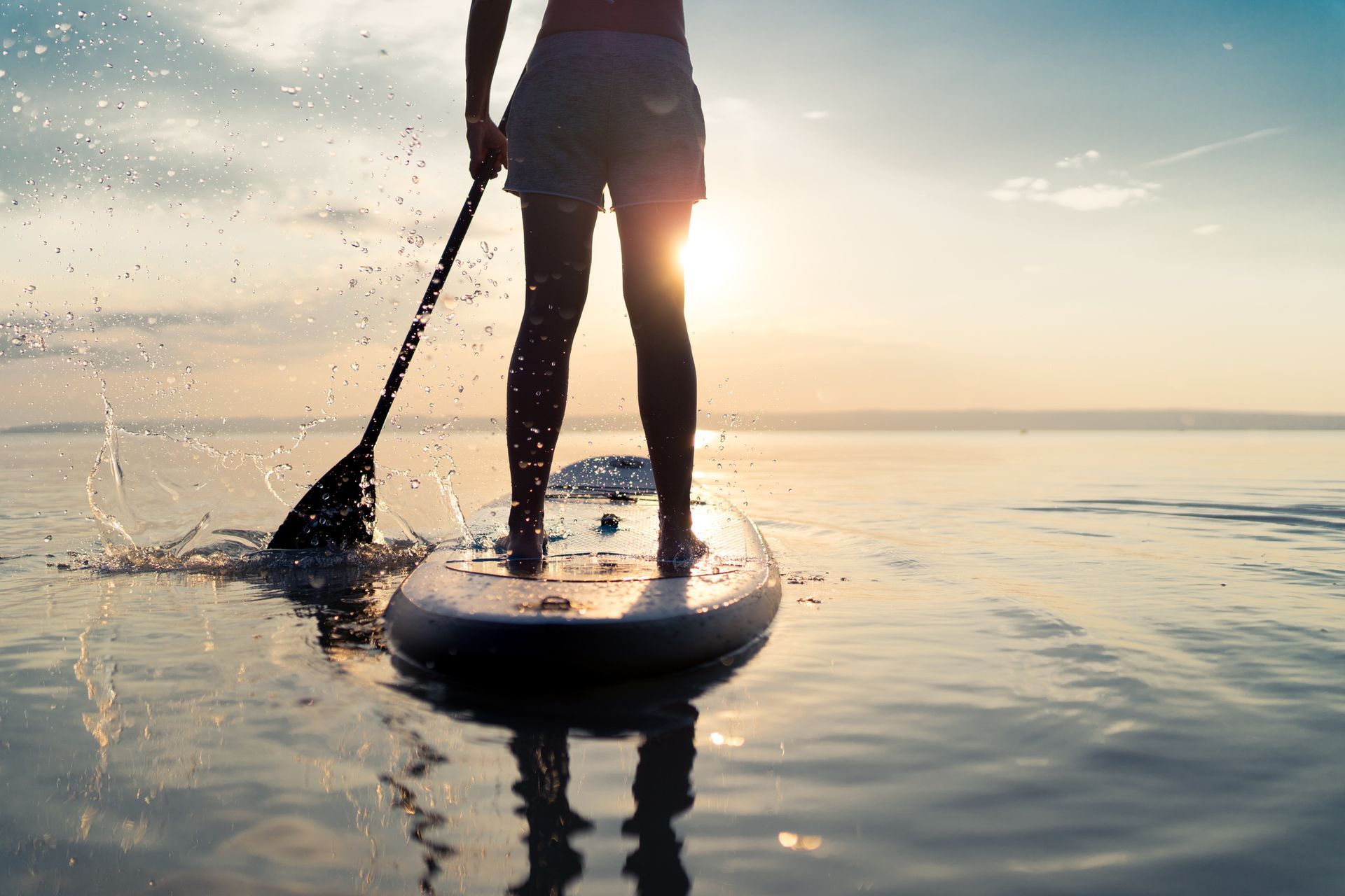 A woman is standing on a paddle board in the ocean.