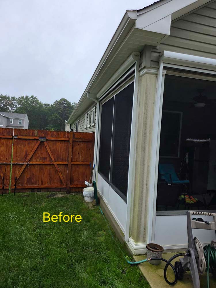 Screened porch exterior with a brown wooden fence on the left and green lawn.