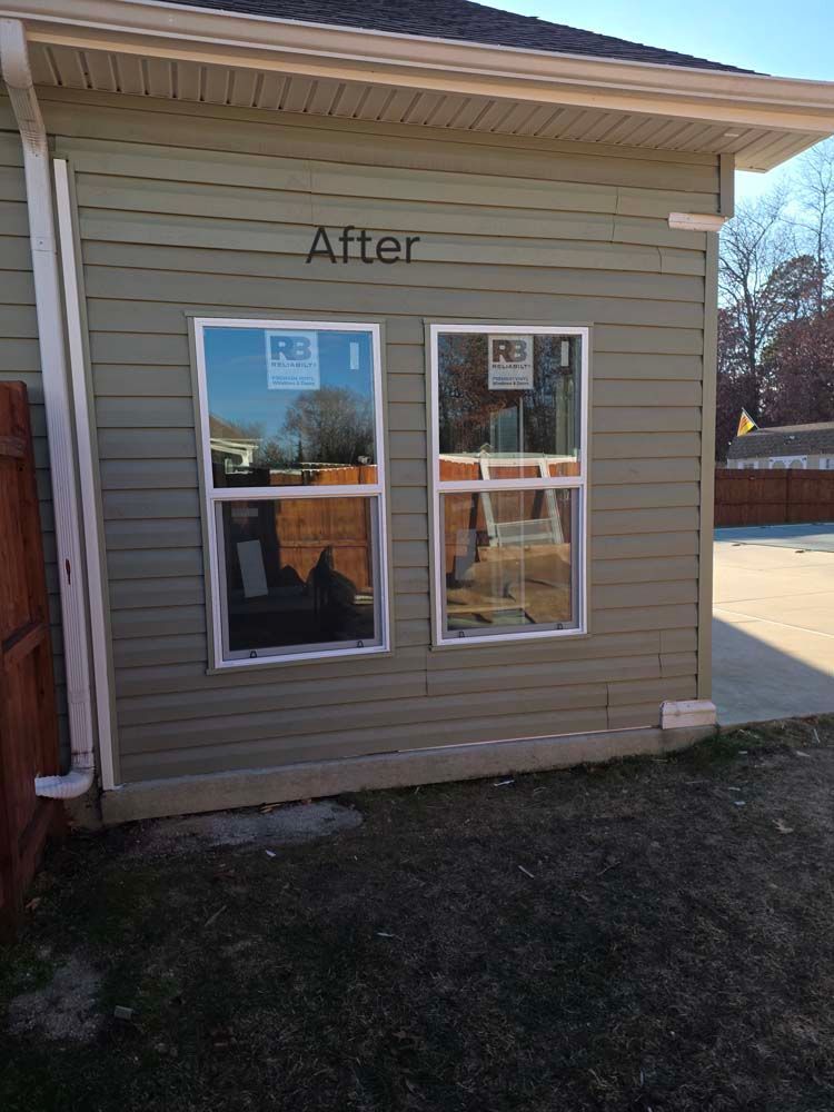 Exterior of a building with two new windows installed in light green siding. 