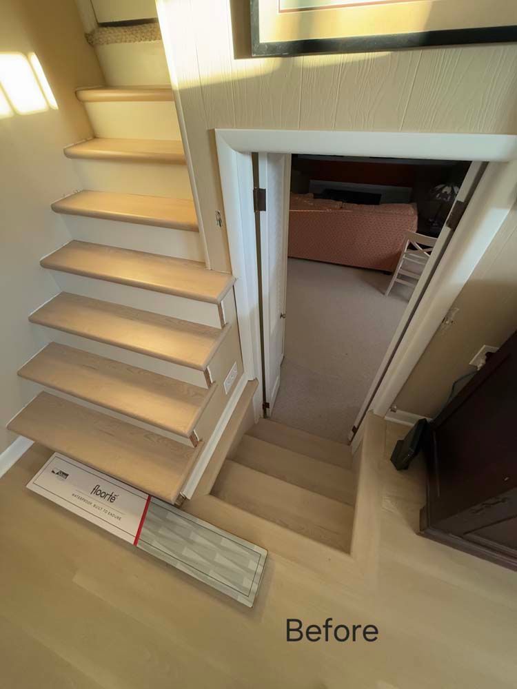 Staircase with light wood steps leading down to a doorway. 
