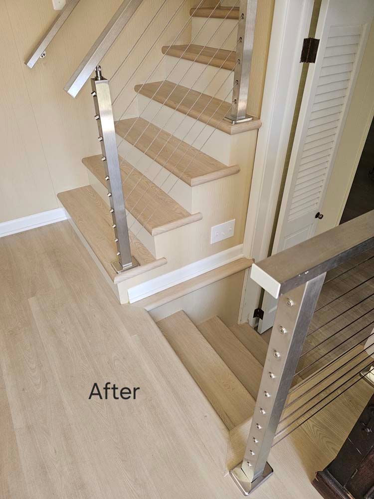 Modern wooden staircase with stainless steel railing and wire cables.