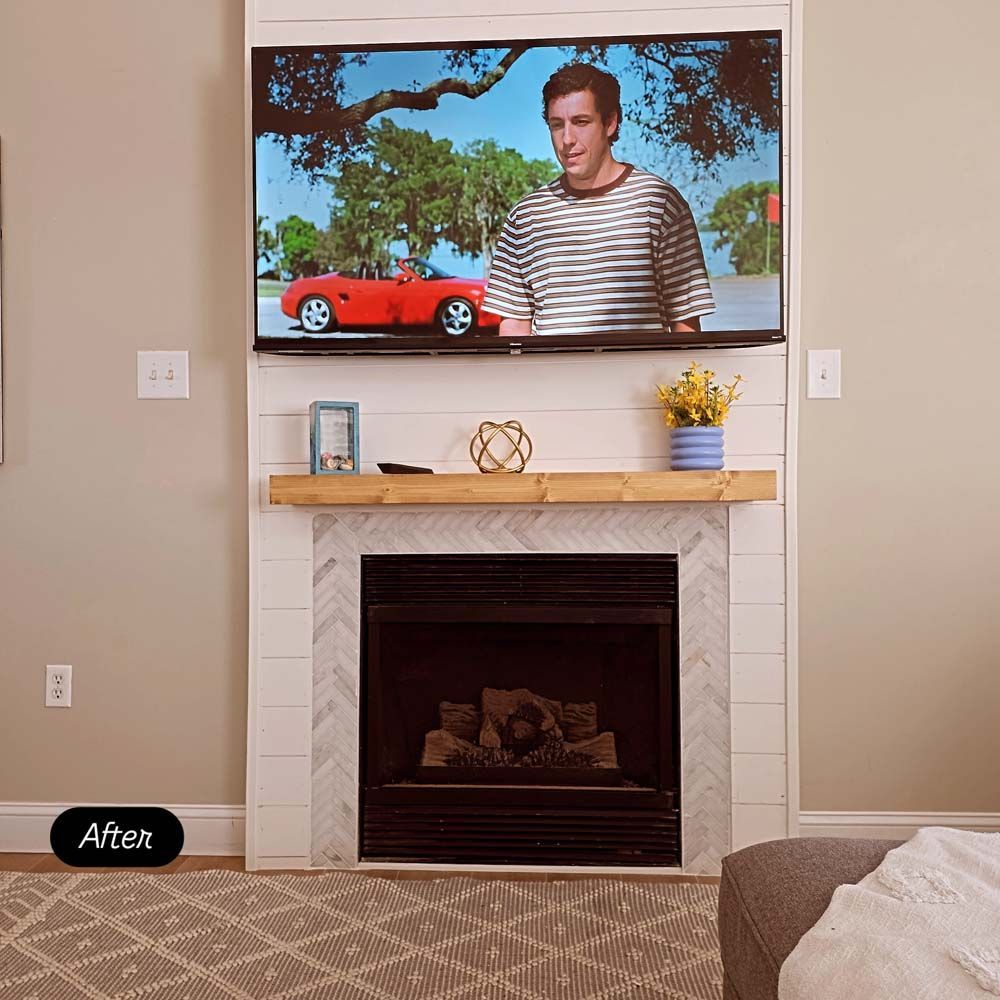 A fireplace with a TV above it, featuring a man in a striped shirt and a red car on screen.