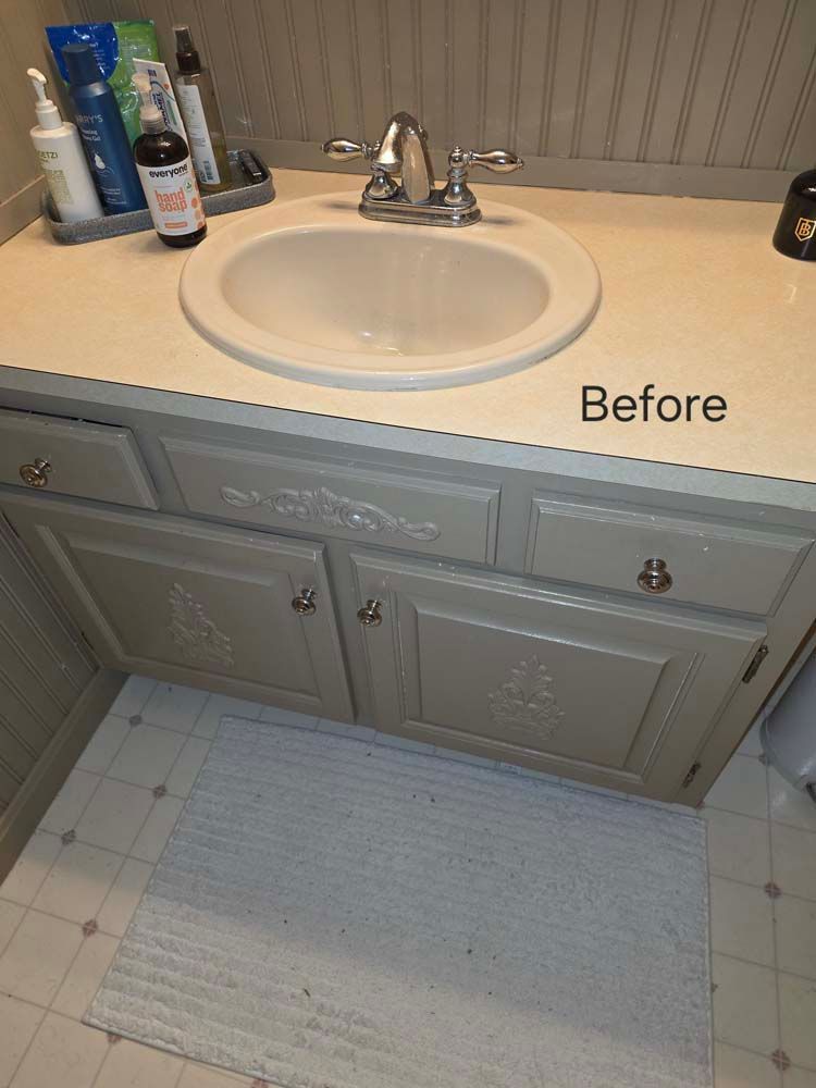 Bathroom vanity with gray cabinets, beige countertop, and oval sink.