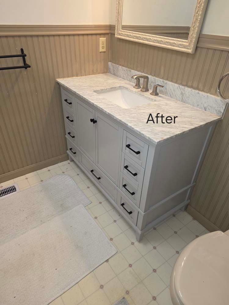 Newly installed white bathroom vanity with marble countertop and black hardware.