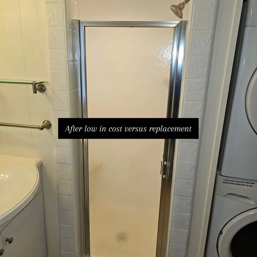Shower door in a white-tiled bathroom, next to a sink and washing machine. Text overlay: 