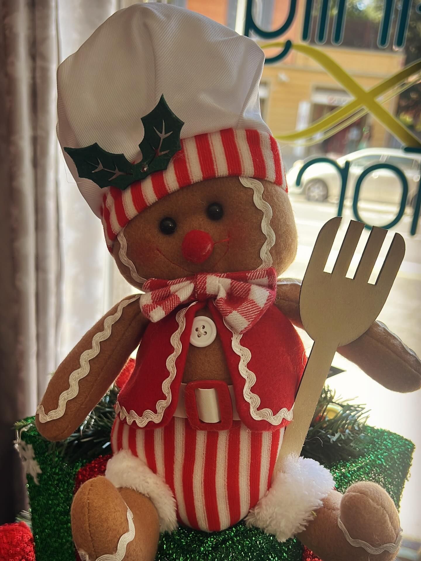 Statuetta di uno chef di pan di zenzero che indossa un abito a strisce rosse e bianche e tiene in mano una spatola, su un regalo decorato.