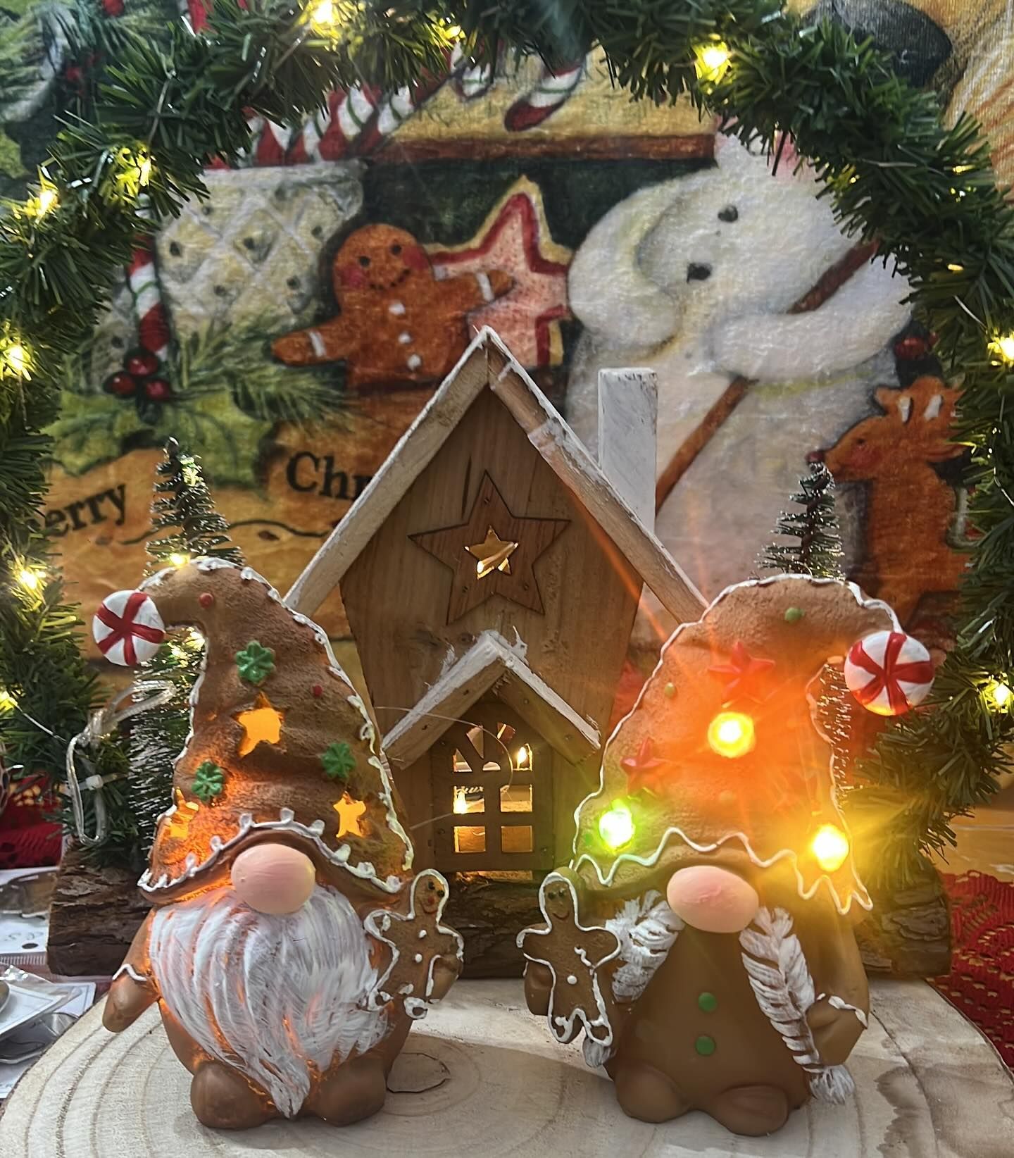 Due gnomi di pan di zenzero con luci, casa di legno e decorazioni natalizie.