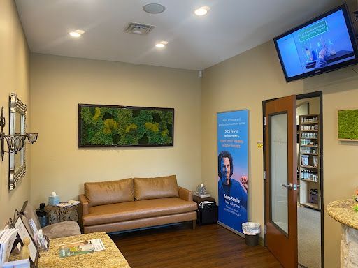 A waiting room with a couch , table , and television.