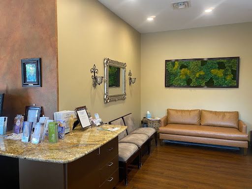 A waiting room with a couch , chairs and a counter.