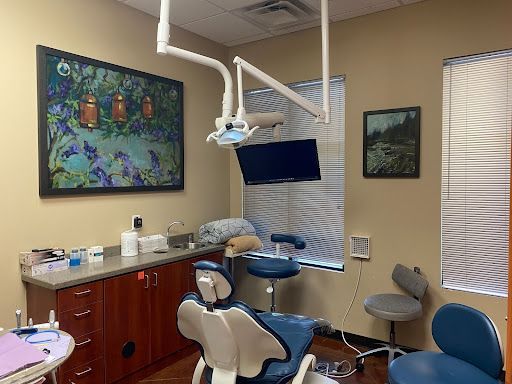 A dental office with a dental chair and a painting on the wall.