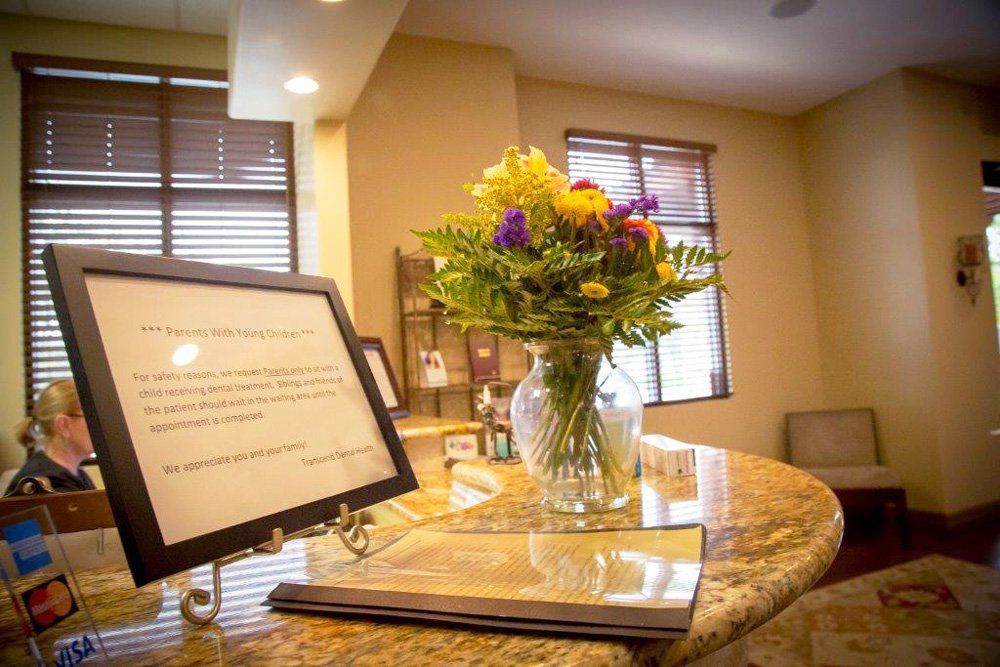 A vase of flowers is on a counter in a dental office.