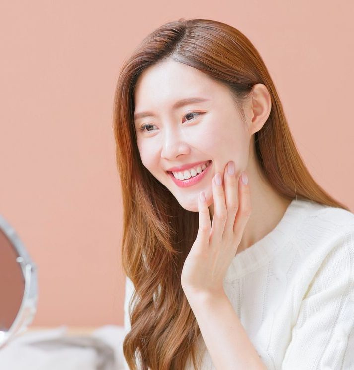 A woman is sitting in a dental chair while a dentist examines her teeth.