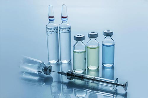 A group of bottles and a syringe on a table.