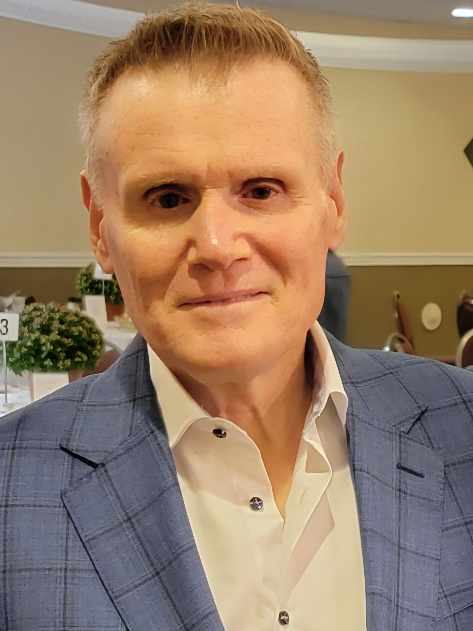 A man in a blue suit and white shirt is smiling for the camera.