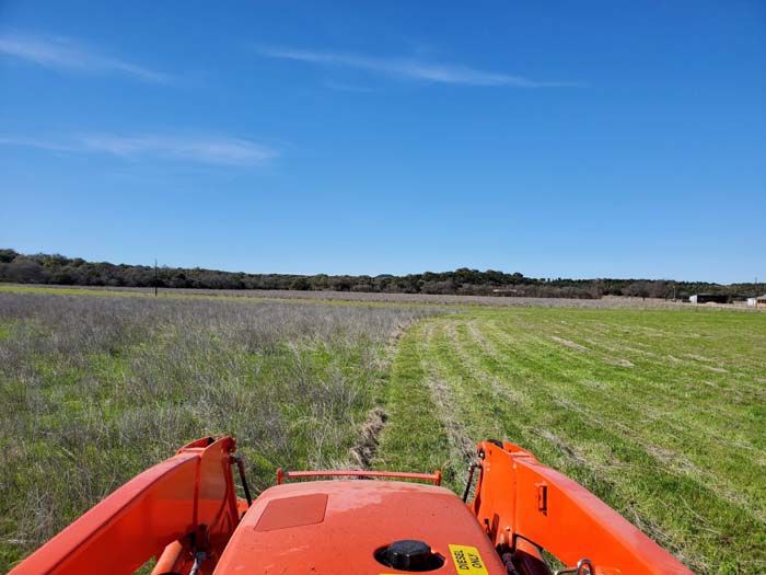 A person is driving a tractor through a grassy field.