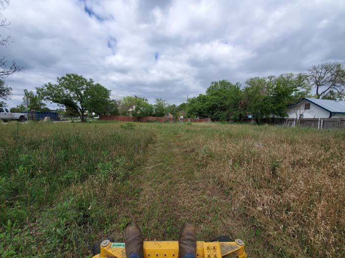 A person is riding a yellow lawn mower through a grassy field.