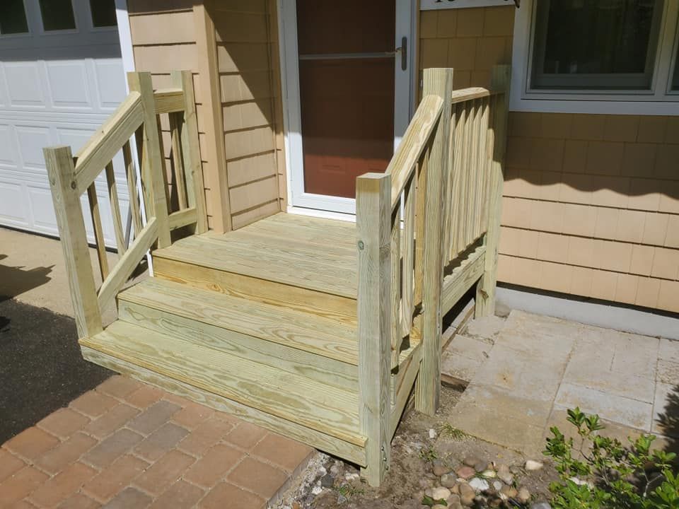 A new wooden front porch with two steps and handrails leading to a residential home entrance.