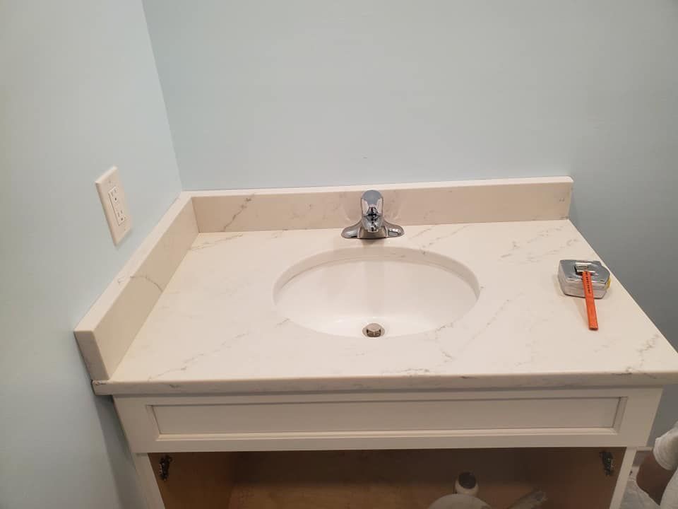 A cream-colored vanity countertop with a sink and faucet installed against a light blue wall.