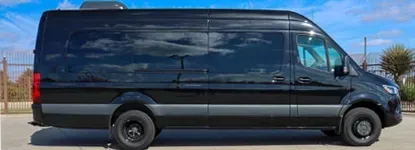 Black van with tinted windows parked outdoors on a sunny day.