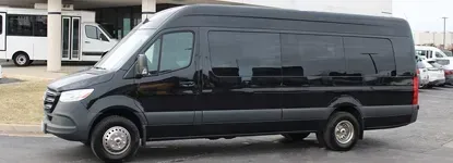 Black passenger van parked near a building. Tinted windows, silver wheels.