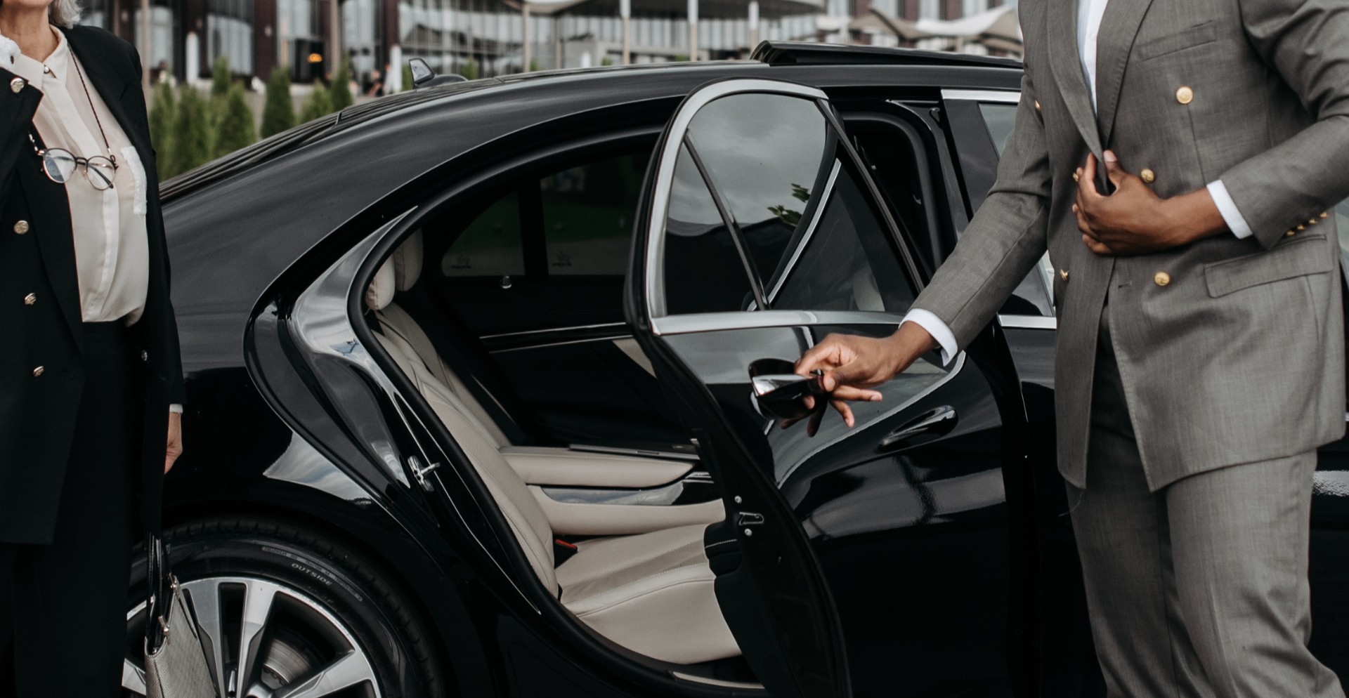 Black Mercedes-Benz sedan parked in front of a wooden wall.