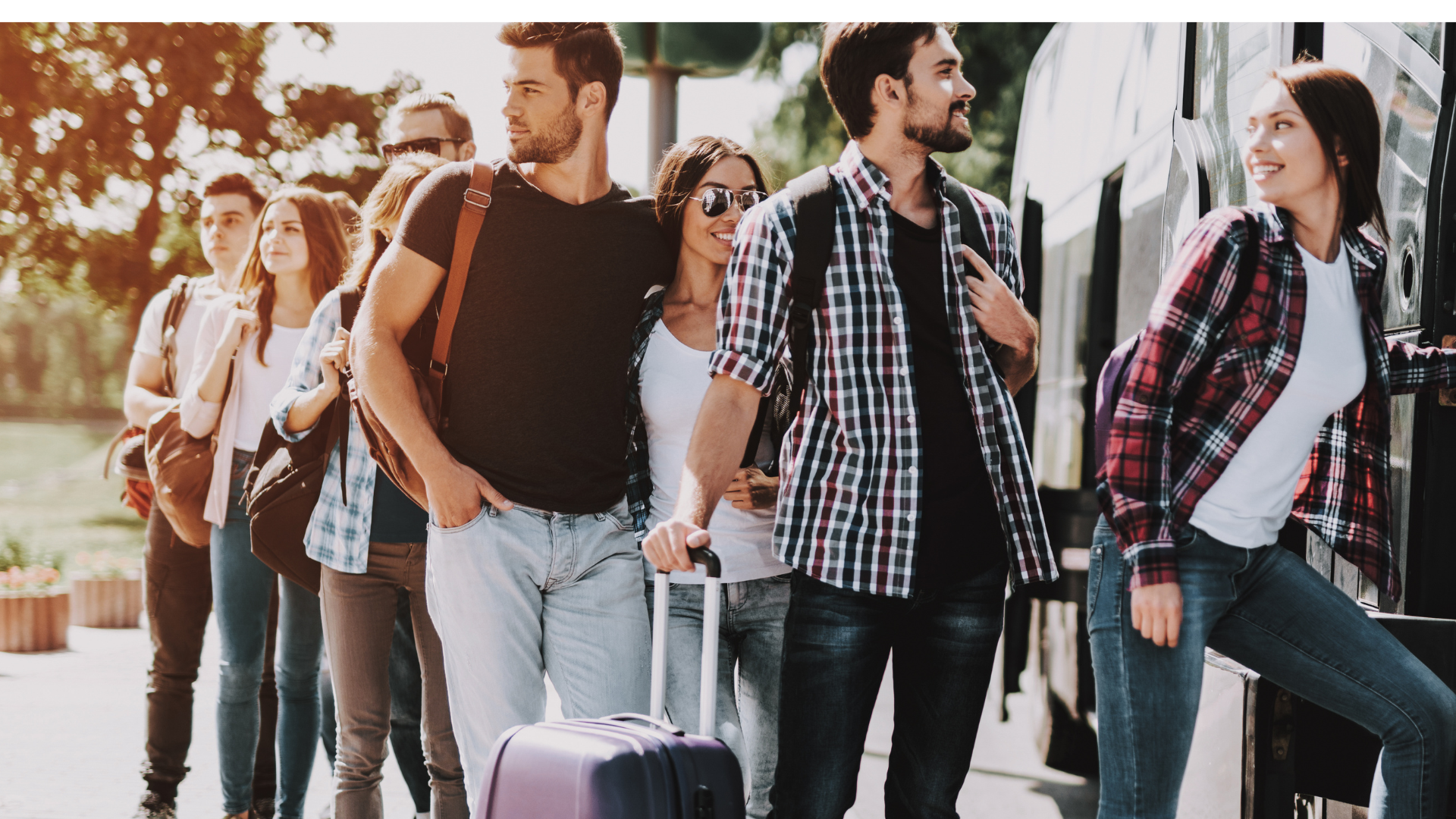 Group of young people boarding a bus, standing in a line outside; sunny day.