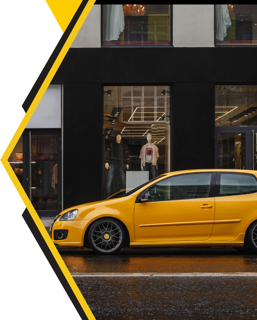 A yellow car is parked in front of a store