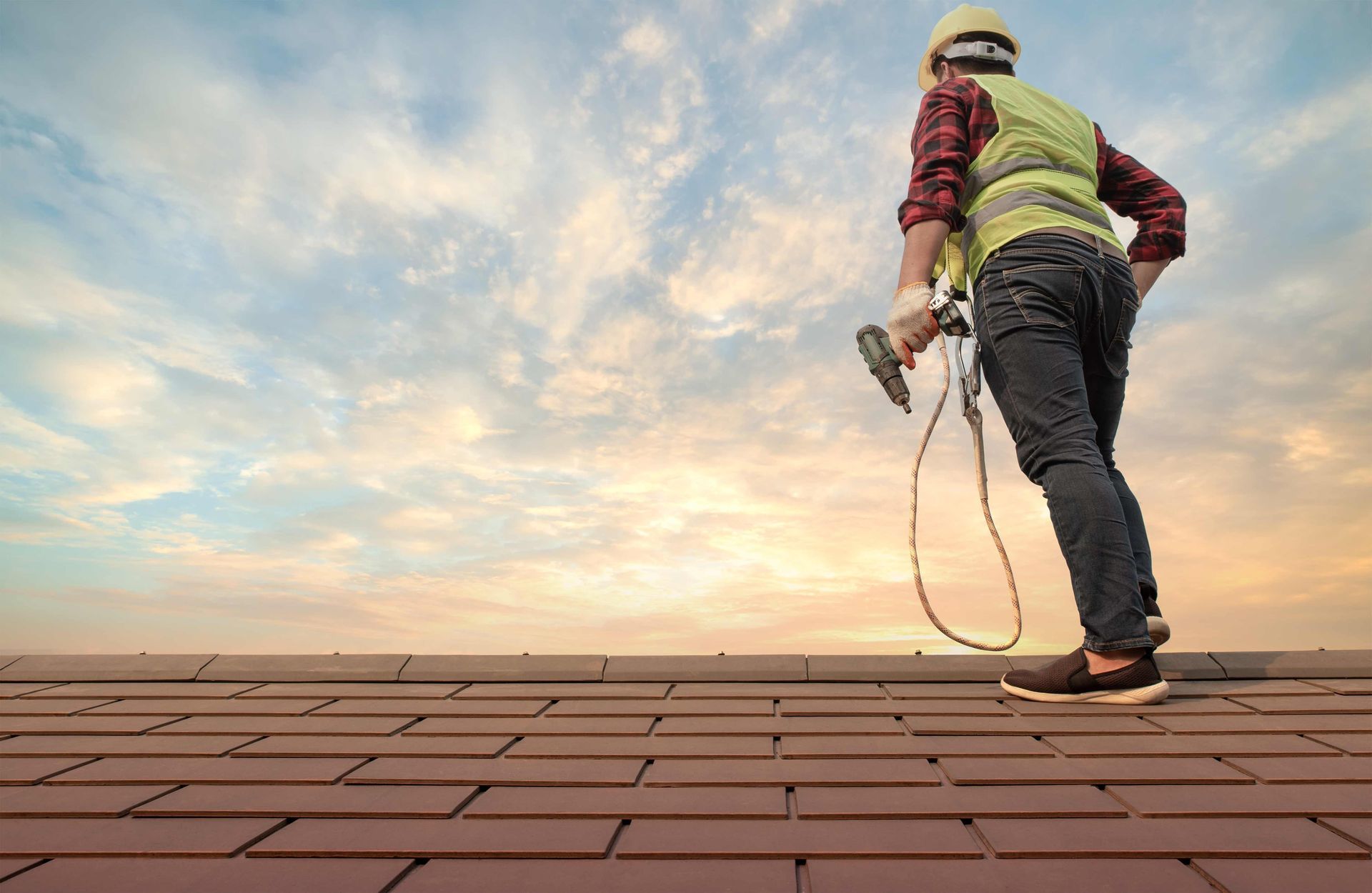A roofer installing cement tiles safely for a residential roof by a trusted roofing company. A roofer installing cement tiles safely for a residential roof by a trusted roofing company.