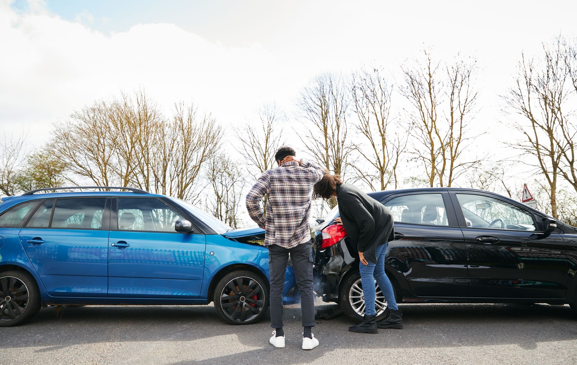 Two drivers inspecting vehicle damage after a car accident