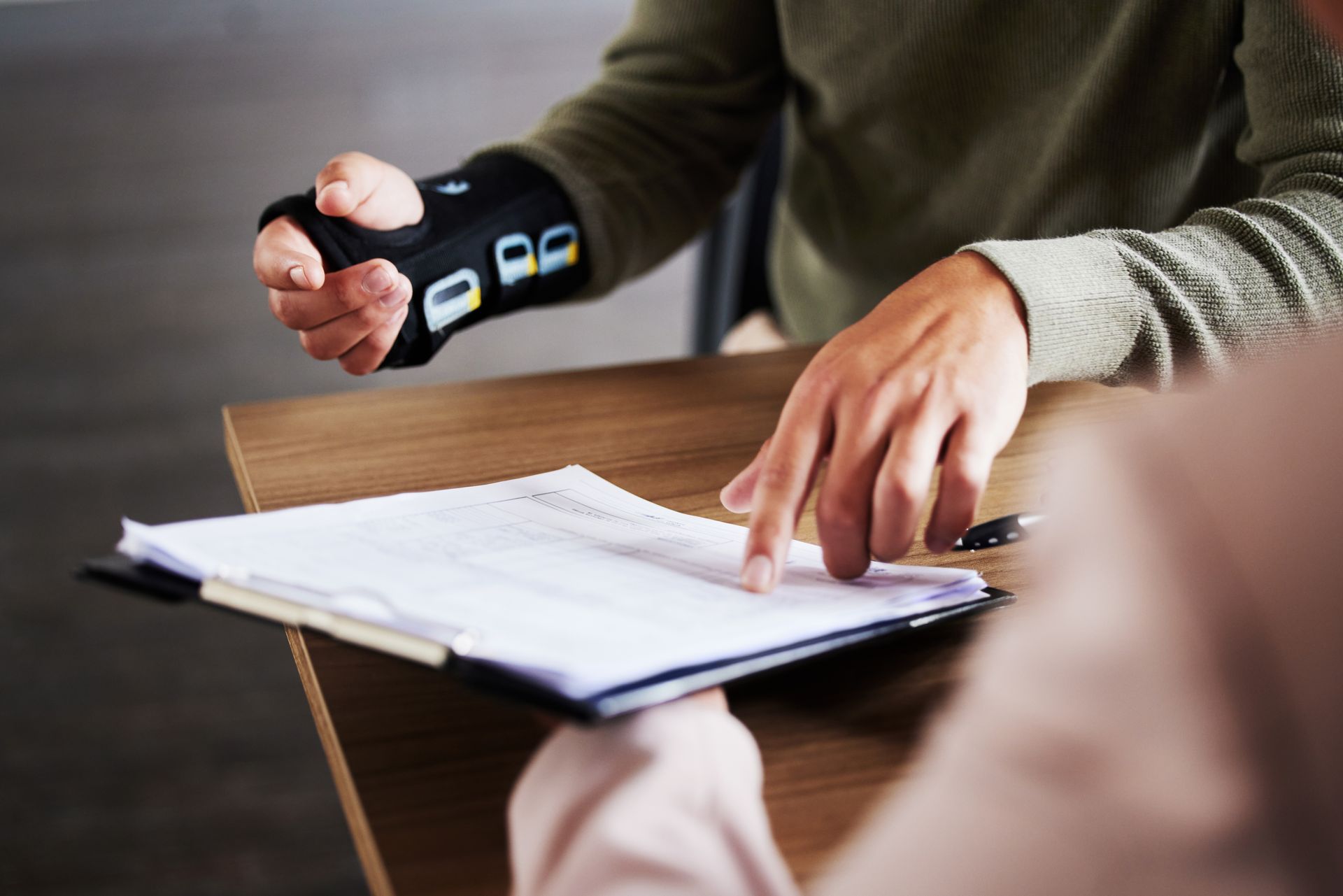 An injured client in a wrist brace reviewing accident paperwork with an injury attorney.