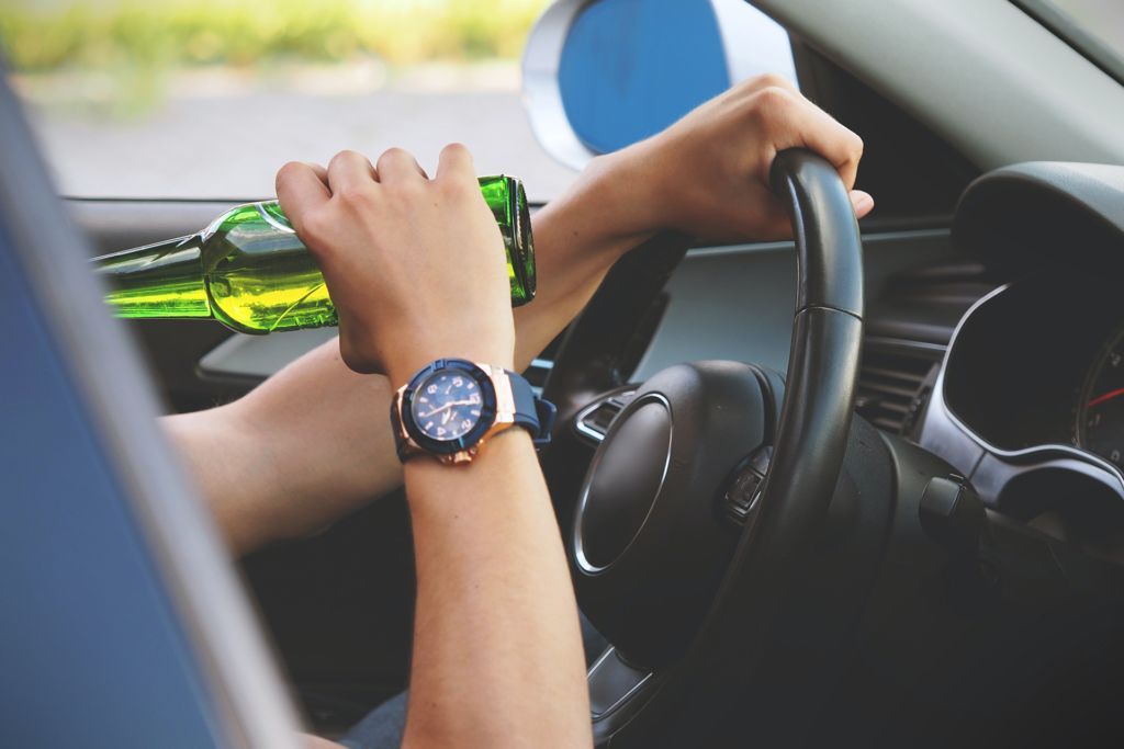 Person drinking from a bottle while driving a car