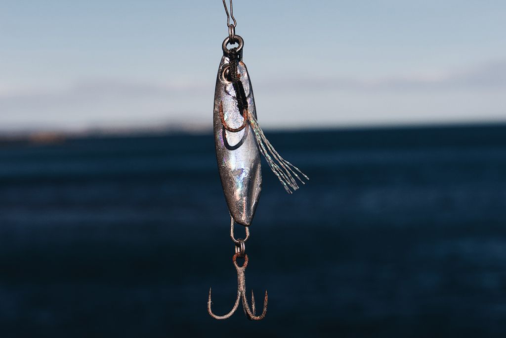 Fishing lure with treble hook against a blurred ocean backdrop