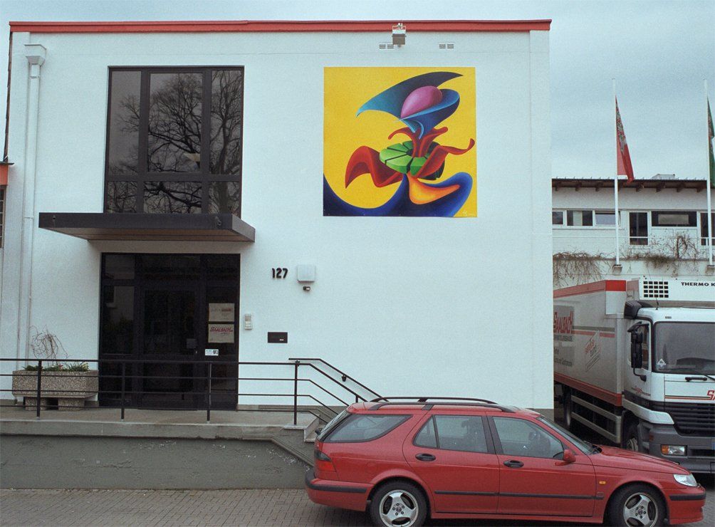 Abstraktes Bild mit farbenfrohen Formen der Künstlerin Benita von Wendt, das an eine Frau mit Halskrause erinnert und nun an seinen endgültigen Platz, das Gebäude des Auftraggebers montiert ist. Gemalt mit Acrylfarben auf Kunststoffplatte.