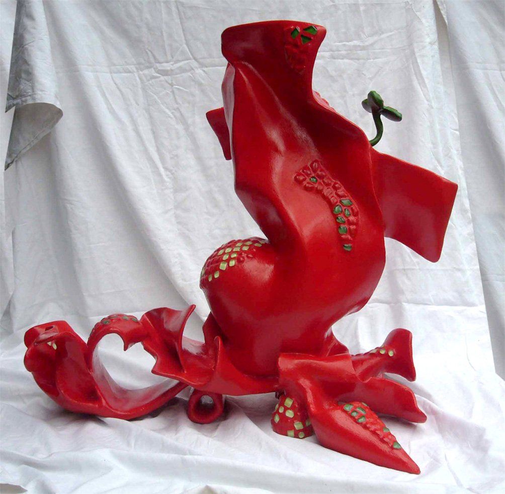 Abstrakte Plastik aus Pappmasché der Künstlerin Benita von Wendt. Titel: Daisy. Die abstrakte Skulptur ist rot mit hellgrünen Mosaiksteinen, anstatt eines Kopfes kommt aus ihrer Mitte heraus eine Blume. Die Plastik erinnert etwas an Daisy Duck, sie zieht eine Schleppe hinter sich her und hat übergroße Pömps an. Seitenansicht rechts.