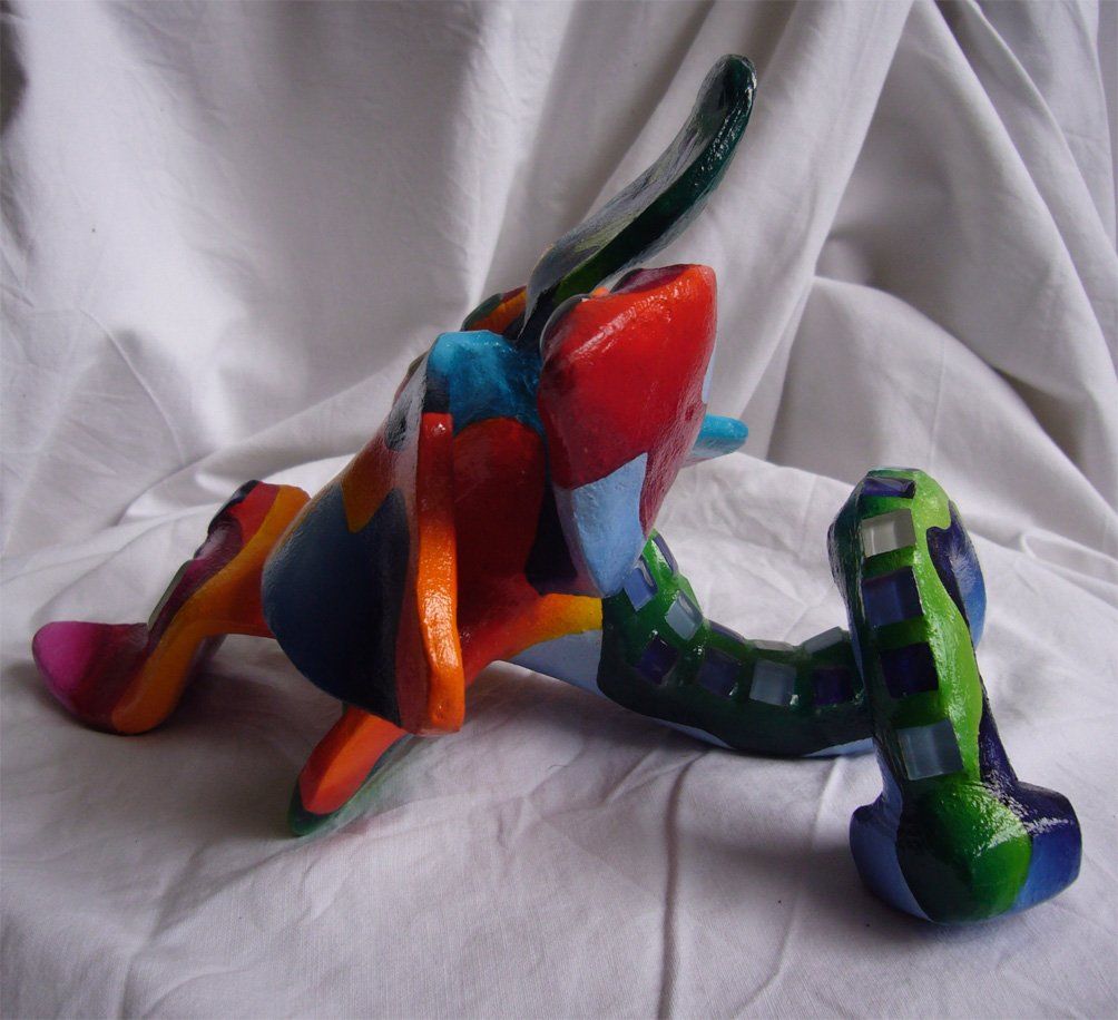 Plastik aus Pappmasché der Künstlerin Benita von Wendt. Titel: Fleur d'espoir 2. Bunte Skulptur die eine kleine sechsblätterige Blume, die auf dem Boden liegt darstellt. Die Blume ist mit bunten, abstrakten Ornamenten bemalt und mit Mosaiksteinen besetzt. Seitenansicht links.