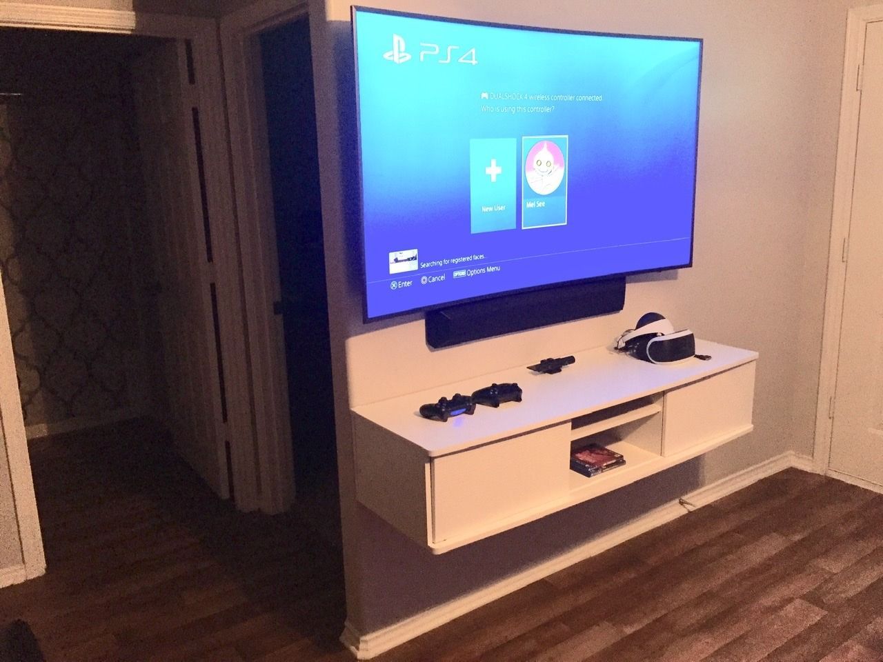 A flat screen tv is mounted on a wall above a shelf.