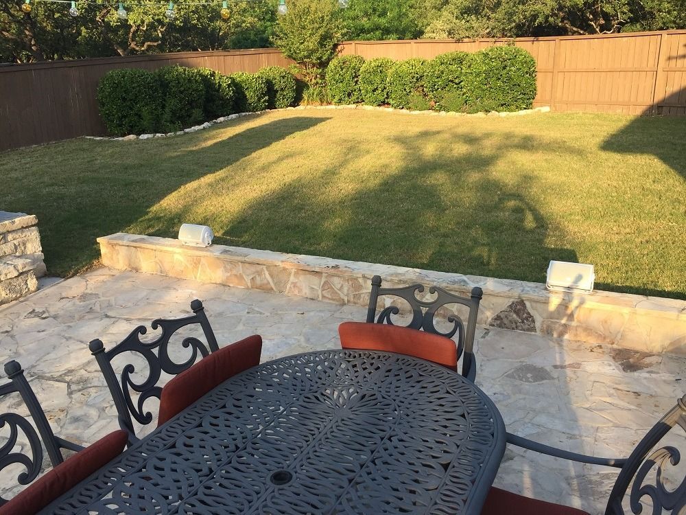 A patio with a table and chairs and a large lawn in the background