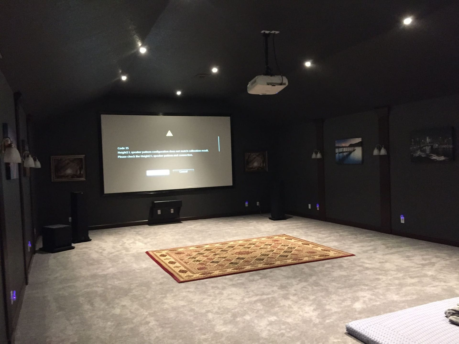 A home theater with a large screen and a rug on the floor.