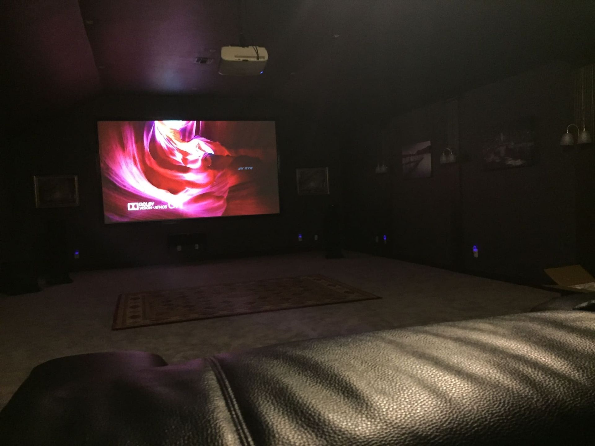 A dark room with a couch and a projector screen.