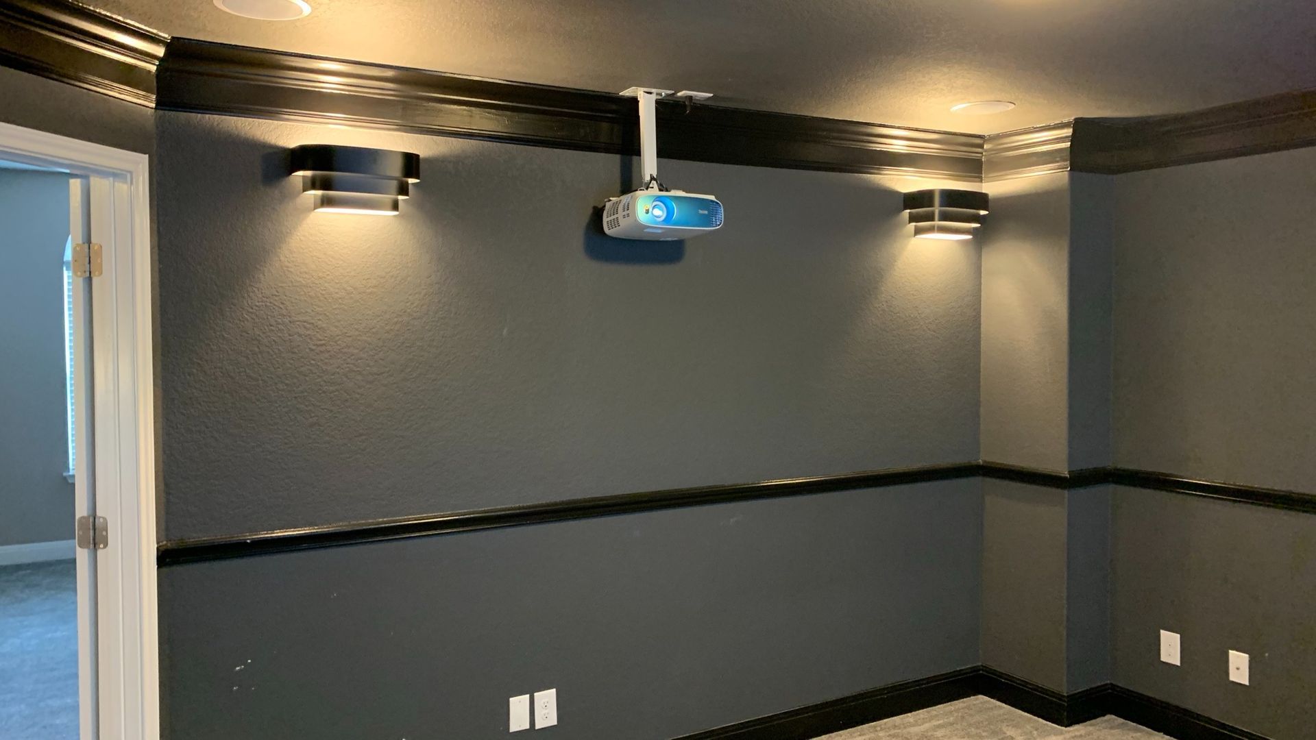 A room with a projector hanging from the ceiling.