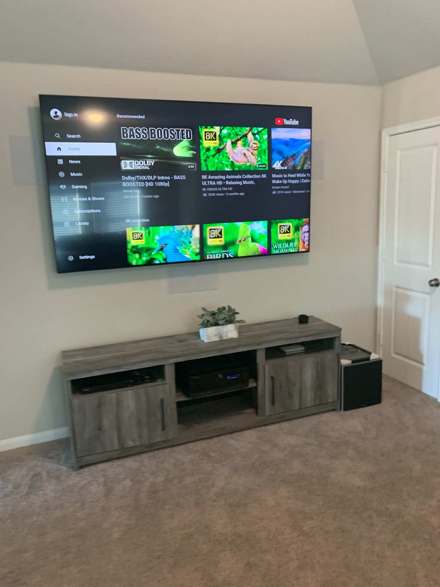 A large flat screen tv is mounted on a wall above a wooden entertainment center.