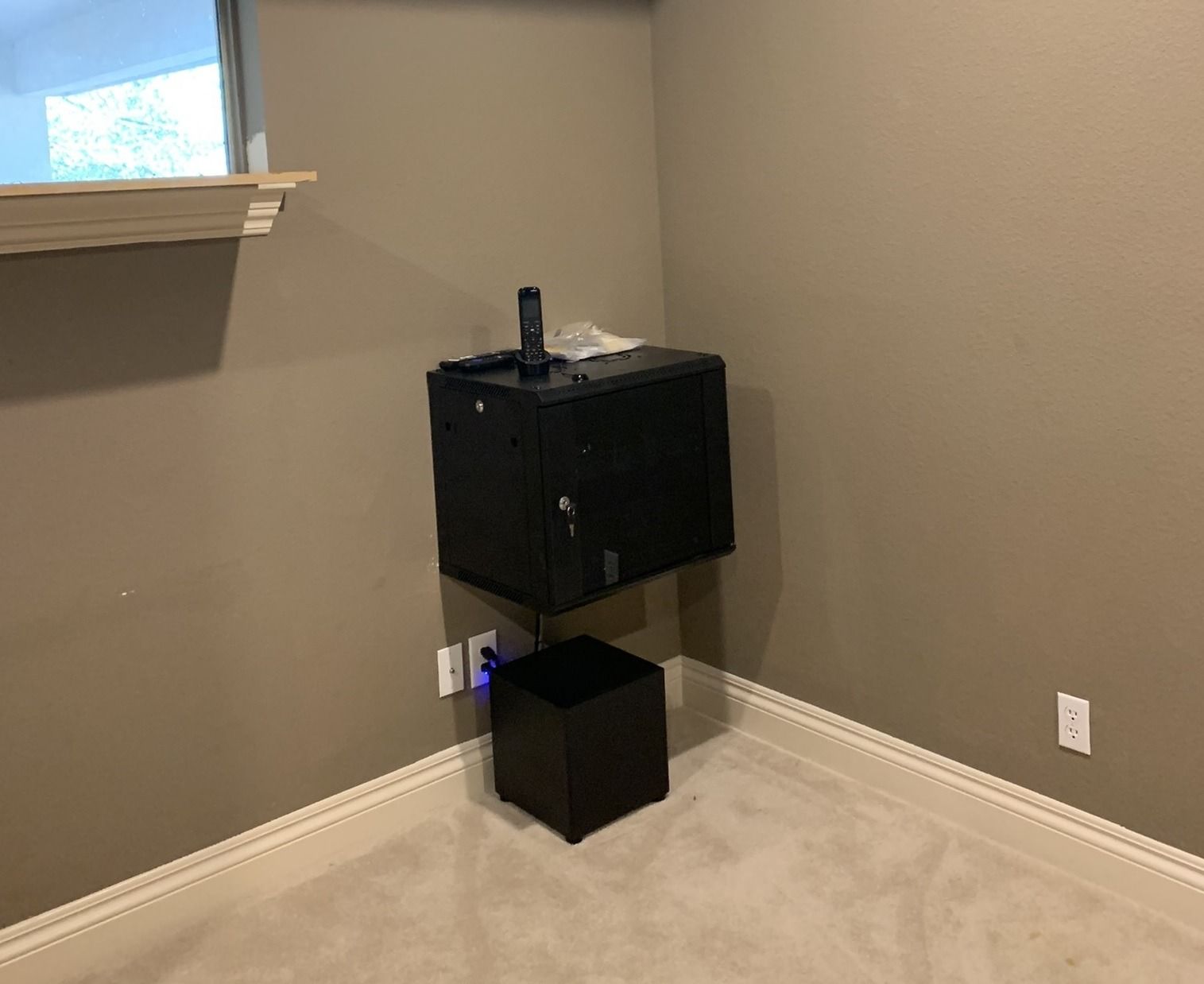 A room with a microwave and a stool in it.