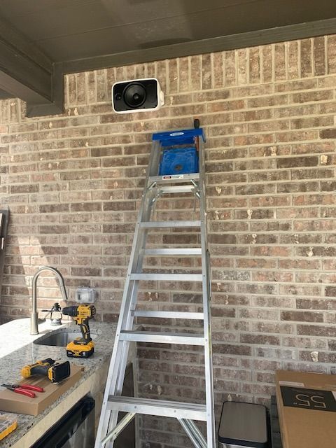 A ladder is hanging on a brick wall next to a sink.