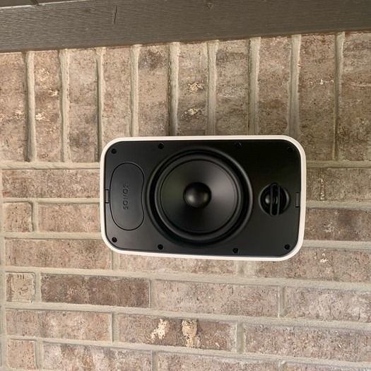 A speaker is mounted on a brick wall.