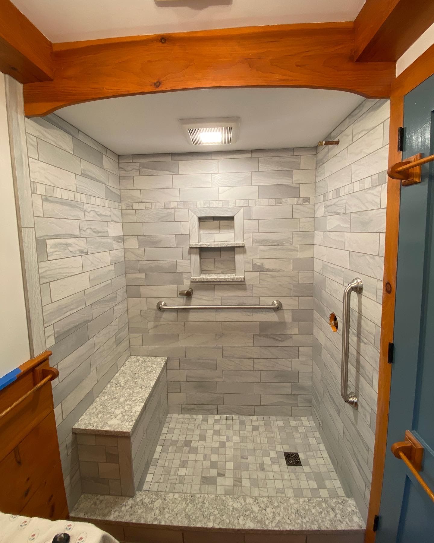 A bathroom with a walk in shower and a bench.